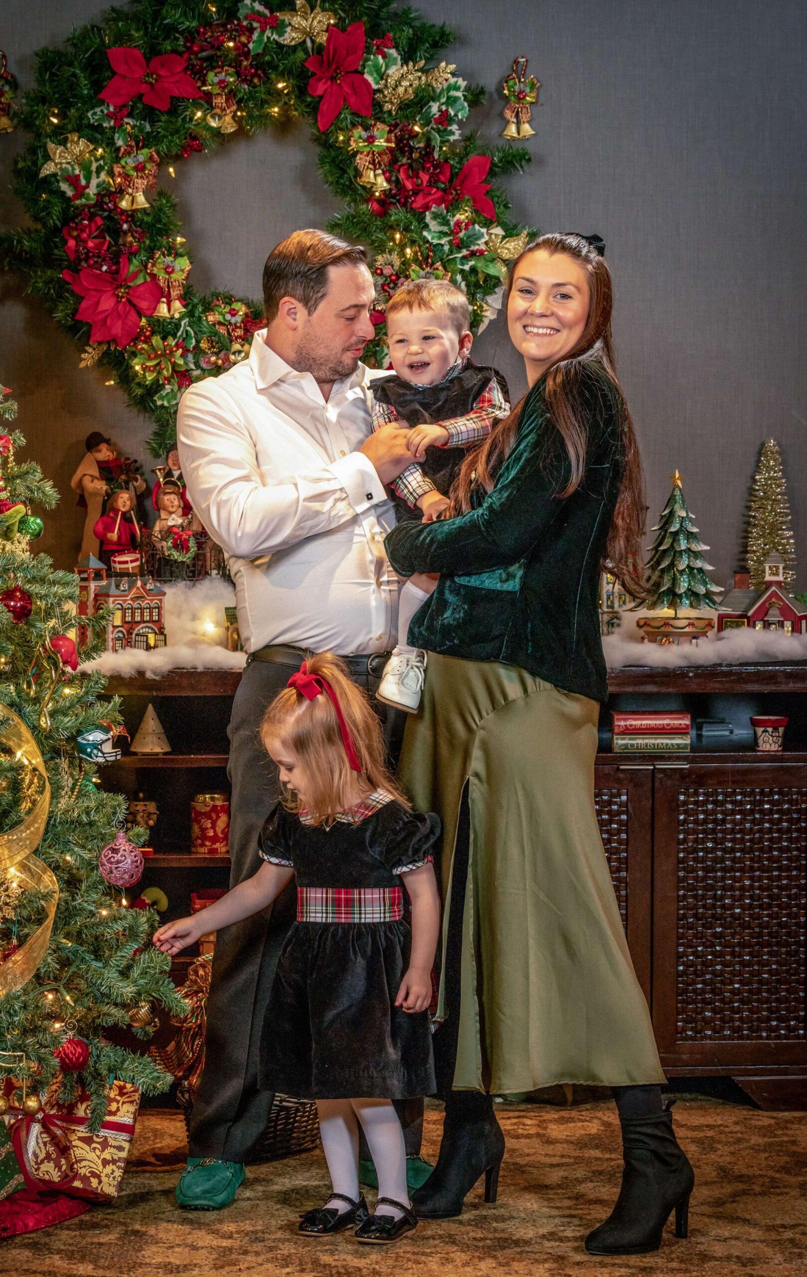 family laughing and posing against a festive christmas tree